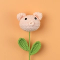 Gros plan d'une fleur cochon rose tricotée à la main avec feuilles sur fond orange - Style Cochon Nude