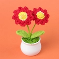 Handgefertigte rote Häkel-Sonnenblume im weißen Topf auf lebendigem orangefarbenem Hintergrund - Rot
