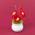 Close-up of handmade crochet flower pot with red blossoms in a white ceramic vase - Plum Blossom Potted Plant Style