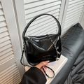 Bolso de mano en cuero negro brillante con correa de cadena sobre libros blancos - Negro