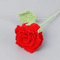 Detailed close-up of handmade crochet red rose with textured green leaves and petals - True Red