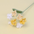Detailansicht handgehäkelter Blumen mit Perlen und grünen Blättern in Makroaufnahme - Dunkelgelb + Hellgelb + Weiß