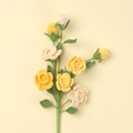 Handmade crochet rose branch with yellow and cream knit flowers on a yellow background - Barbie Rose Branch / Gradient Yellow
