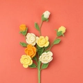 Handmade crochet rose bouquet with warm orange and yellow flowers on matching background - Barbie Rose Branch / Gradient Orange