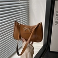 Brown glossy patent leather baguette bag featuring a gold metal bow and sleek shoulder strap - Brown