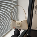 Bolso baguette beige minimalista con hebilla metálica mostrado en una mano elegante - Blanco