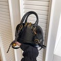 Glänzende schwarze Muscheltasche mit Griffen, goldener Hardware und kleinem Glockenanhänger - Einzelne Tasche / Schwarz