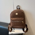 Brown leopard print backpack with gold metal logo and zipper on a black bench - Brown