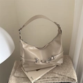 Elegante borsa hobo beige vintage con finiture argento su uno sfondo di una rivista - Bianco