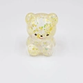 Macro view of a clear yellow bear-shaped squeeze toy with gold star glitter and sequins - Stone Yellow Pearl