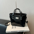 Minimalistische schwarze Lackleder-Beuteltasche mit Metallplakette und Griffen - Schwarz