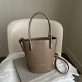 Bolso cubo minimalista de cuero PU marrón con asa y bandolera sobre una silla blanca - Caqui