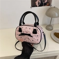 Bolso bowling rosa con lazo negro y correa de bandolera mostrado en una mesa - Blanco