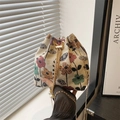 Bolso saco retro étnico con flores cadena dorada y perlas sostenido por una modelo - Colorido