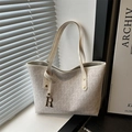 Chic cream-colored monogram tote bag with shoulder strap and R-pendant in natural light - White