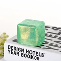 Translucent green ice cube squishy toy with glitter on a white book display - Green