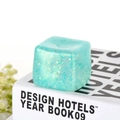 Close-up of translucent mint green ice-cube stress toy with gold glitter flakes - Cyan