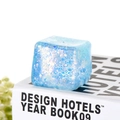 Close-up of blue glitter ice cube squeeze toy showing translucent texture and sparkles - Blue
