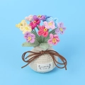 Detail eines handgehäkelten Vergissmeinnicht-Bouquets mit Handmade with Love-Lederetikett - Mehrfarbig