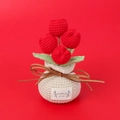 Close-up of handmade crochet red tulips in a gift bag pot with a handmade label - Red