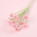 Handmade pink crochet flower branch with white pearl center on a soft pink background - Pink