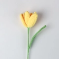 Dettaglio di un tulipano giallo fatto a mano all'uncinetto con trama a maglia e stelo verde - Giallo chiaro