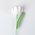 Close-up of a handmade crochet white tulip with green stem and knitted texture details - White