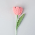 Close-up of handmade pink knitted tulip flower with soft yarn texture and green stem - Peach Pink