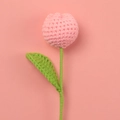 Macro shot of handmade crochet tulip with pink yarn petals and green knit leaf - Peach Pink