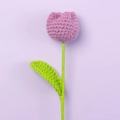 Close-up of handmade crochet tulip with purple yarn texture and green knitted leaves - Deep purple