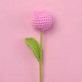 Close-up of a handmade pink crochet tulip flower with green stem on a soft pink background - Rose Purple