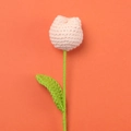 Detailed close-up of a handmade crochet tulip with pink petals and green leaves - Nude
