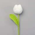 Close-up of handmade white crochet tulip flower with detailed knit texture and green leaf - White