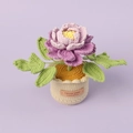 Detail of hand-knitted peony plant in a cream pot with a handmade leather label tag - Gradient Purple Peony (Large Cylindrical Yarn Pot)