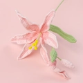 Handmade crochet daylily in pale pink with green stem on soft pink background - Pink