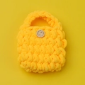 Macro shot of chunky yellow hand-crocheted headphone case with a decorative wooden button - Yellow