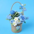 Gros plan d'un panier de fleurs crochetées à la main avec fleurs bleues et blanches et ficelle - Série Bleue