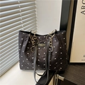 Black tote bag with white bow texture, gold chain handles, and a stylish brand label - Black