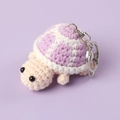 Close-up of pink and purple handmade crochet turtle keychain with a metal lobster clasp - Purple
