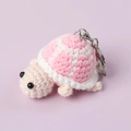 Macro view of a handmade pink and beige crocheted turtle keychain with silver metal ring - Pink
