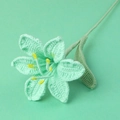 Detail einer handgehäkelten Lilienblume mit grünen Blütenblättern und gelben Staubblättern - Aquagrün