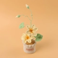 Close-up of handmade crochet yellow flowers in a knitted pot with handmade leather label - Yellow