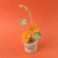 Handmade crochet orange blossom potted plant with green leaves and a handmade label - Orange