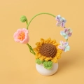 Handgefertigte gehäkelte Sonnenblumen-Topfpflanze mit Perlen auf gelbem Hintergrund - Sonnenblumenkorb-Topfpflanze (mit Maiglöckchen + Vergissmeinnicht) / Rosa