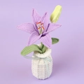 Close-up of handmade crochet purple lily flower in white woven vase with blue ribbon - Purple Lily-White Vase