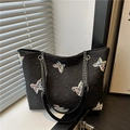Borsa tote nera con ricami farfalla colorati e tracolla a catena su sfondo decorativo - Nero