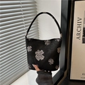 Minimalist black bucket bag with white floral patterns and textured fabric strap - Black
