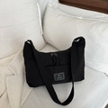 Borsa a tracolla minimalista in nylon nero con etichetta tessuta su un letto - Nero