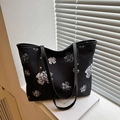 Black canvas tote bag with white floral patterns and elegant leather trim accents - Black