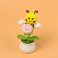 Detail of handmade crochet yellow bee holding a pink rose in a white ceramic vase - Bee Gathering Nectar - Gradient Pink Rose